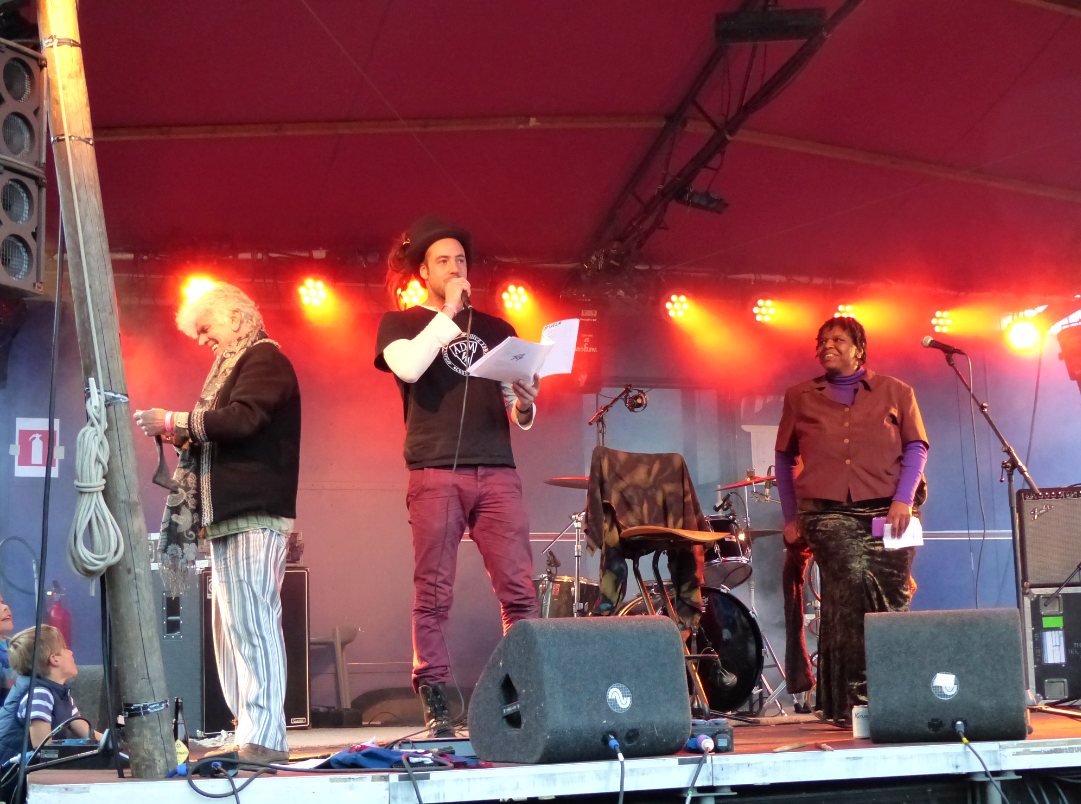 Bram Schrijnen performing on stage, with Hans Plomp and Maxi McNaughty